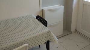 A small dining area with a table covered by a polka-dotted tablecloth, a chair, and a white cabinet. - Apartmani Meri (Vodice)