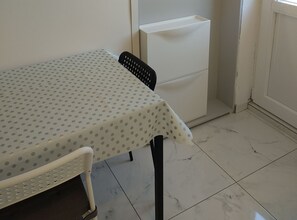 A small dining area with a table covered by a polka-dotted tablecloth, a chair, and a white cabinet.