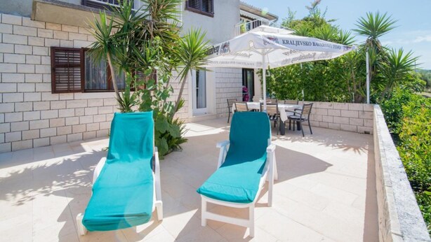Une terrasse avec deux fauteuils de jardin, une table et un parasol.