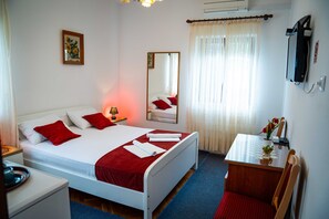 Ein Hotelzimmer mit Bett, Schreibtisch, Stuhl, Spiegel und Fernseher.