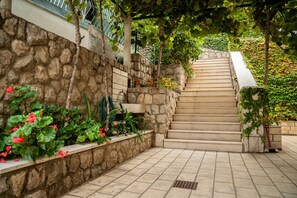 Eine Steintreppe führt zu einer höheren Ebene, umgeben von Grünpflanzen und blühenden Blumen.