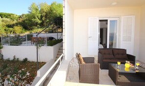 A balcony with wicker furniture, a glass table, and two drinks. - Apartment Dubreta With Balcony (Konavle)