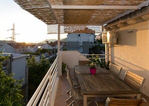 A balcony with a wooden table, chairs, and a potted plant. - Apartment Marlo - Two-bedroom Apartment With Balcony (Dubrovnik)