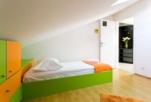 A bedroom with a green bed, white bedding, a wooden floor, and a small orange rug. - Apartment Marlo - Two-bedroom Apartment With Balcony (Dubrovnik)