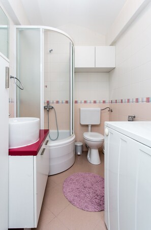 A bathroom with a shower, toilet, sink, and a small rug. - Apartment Marlo - Two-bedroom Apartment With Balcony (Dubrovnik)