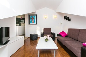 A modern living room with a white coffee table, a brown sofa, a TV, and a painting on the wall. - Apartment Marlo - Two-bedroom Apartment With Balcony (Dubrovnik)