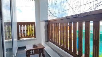 Un balcón con una mesa de madera y vista a un jardín.