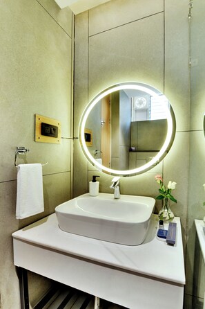 A modern bathroom with a large mirror, a sink, and a towel rack.