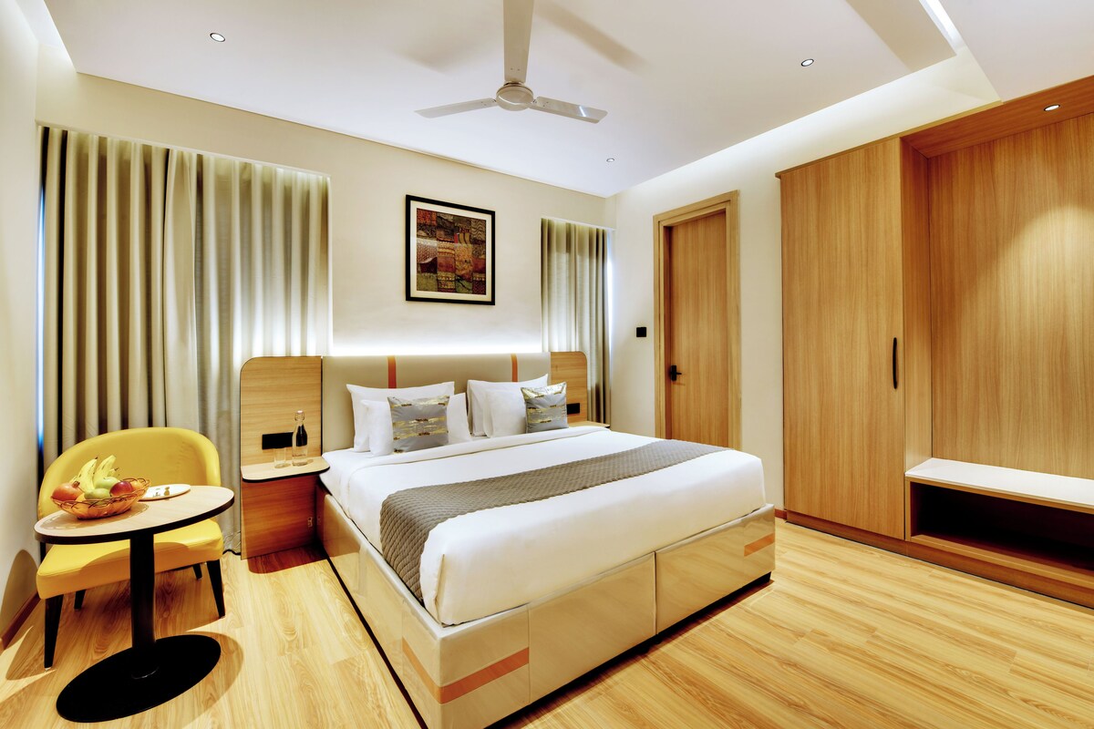 A hotel room with a bed, bedside table, chair, and a wardrobe.
