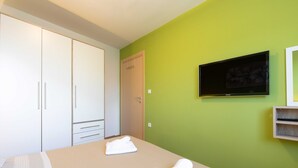 Ein Hotelzimmer mit einem Bett, einem Fernseher, einem Kleiderschrank und einer grünen Wand.