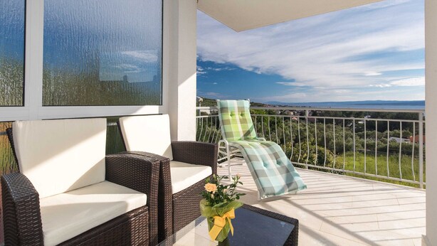 Ein Balkon mit Korbmöbeln, Meerblick und einem Bild an der Wand.