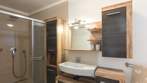 Ein modernes Badezimmer mit einer Duschkabine aus Glas, einem integrierten Waschbecken und Holzschränken.