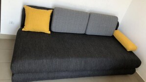 A dark grey sofa with two grey cushions and a yellow pillow against a white wall. - Apartmani Villa Borzic - One Bedroom Apartment With Terarce (Omis)