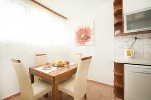 A dining area with a wooden table, four chairs, and a breakfast setting including fruits and a croissant. - Apartment Hanna - Two Bedroom Apartment (Split)