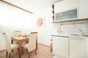 A compact kitchen with a dining table, chairs, a microwave, and a dishwasher. - Apartment Hanna - Two Bedroom Apartment (Split)