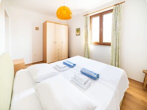 A hotel room with a double bed, a wardrobe, a window with curtains, and a hanging light fixture. - Villa Oliva - Two Bedroom Villa With Terrace and Swimming Pool (Konavle)