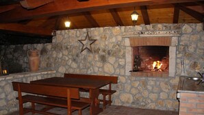 Un mur en pierre avec une cheminée, une table et des bancs en bois, ainsi qu’une étoile décorative suspendue.