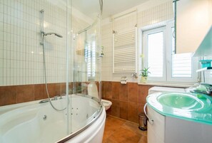 Ein Badezimmer mit einer Duschkabine, einer Badewanne, einer Toilette und einem Waschbecken mit einer grünlichen Arbeitsplatte.