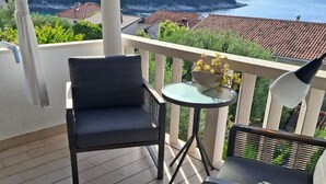 A balcony with a chair, a small table, and a potted plant. - Three Bedroom Apartment With Terrace and sea View (Postira)