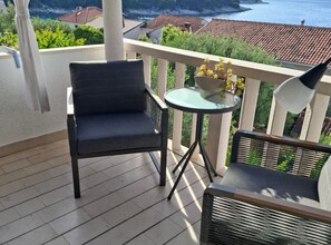 Ein Balkon mit Stuhl, Tisch und einer Topfpflanze.