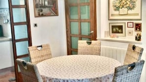 A dining area with a round table, wicker chairs, and a hanging light fixture. - Three Bedroom Apartment With Terrace and sea View (Postira)