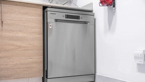 Samsungin jääkaappi keittiössä, jossa on puinen kaappi ja valkoisilla laatoilla päällystetty lattia.