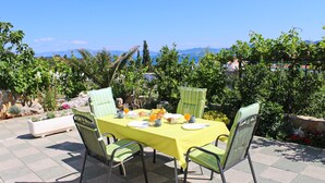 Un espacio de comedor al aire libre con una mesa dispuesta para el desayuno, rodeada de sillas y con vistas a un paisaje pintoresco.