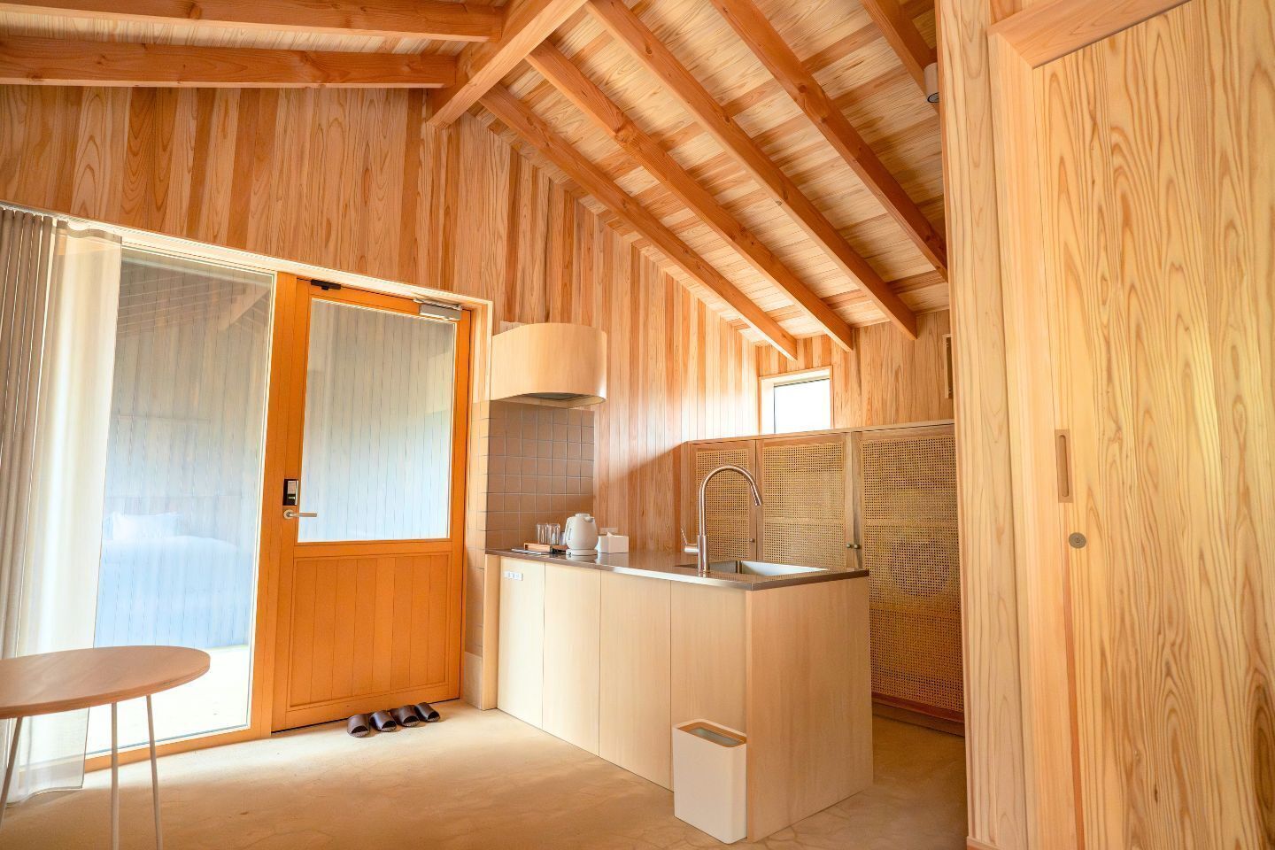 A compact kitchen with wooden walls, a sink, a stove, and a small table.