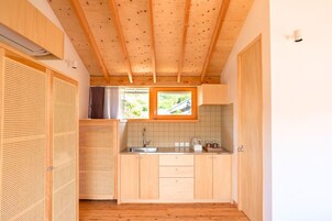 Cocina compacta con armarios de madera, salpicadero de azulejos y ventana con vistas a la vegetación.