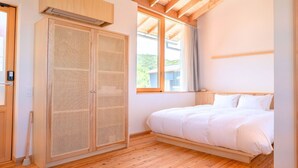 Un dormitorio con una cama de madera, un ventanal grande y un armario de madera.