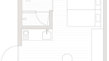 A floor plan of a hotel room with a bathroom, a small kitchenette, and a circular seating area.
