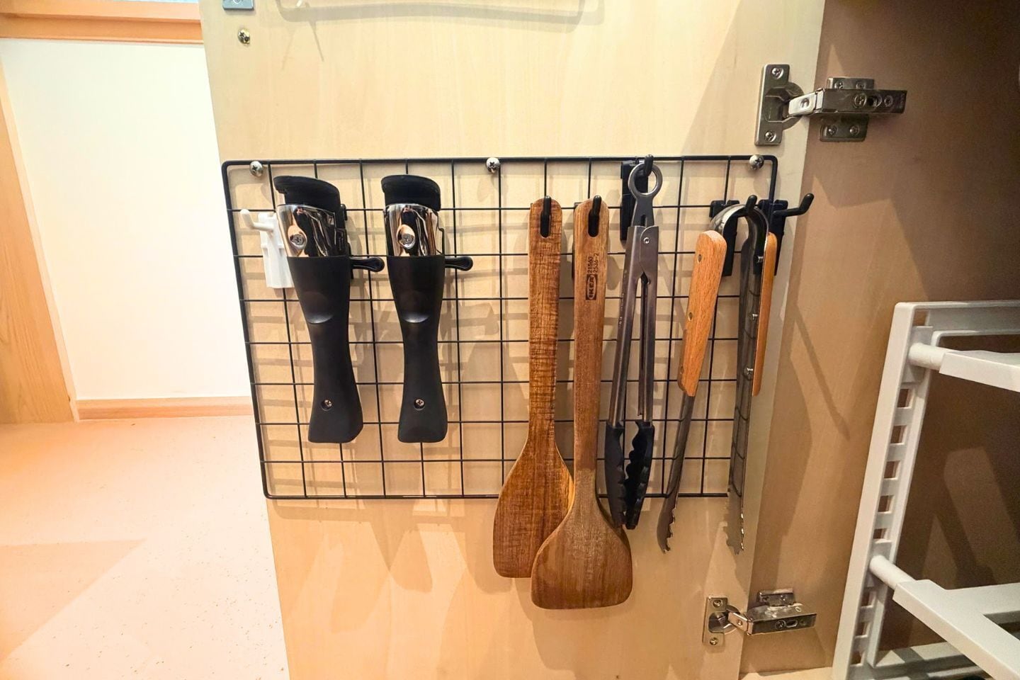 Una cocina con un colgador de utensilios en la pared que contiene diferentes herramientas de cocina.