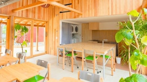 Un interior moderno con techo de madera, una mesa de comedor central con sillas y una cocina con electrodomésticos.