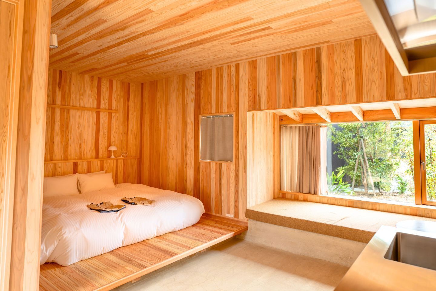 A wooden room with a bed, a window seat, and a desk.