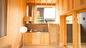 Interior de madera con área de cocina, que incluye armarios, un lavamanos y una ventana con cortinas.