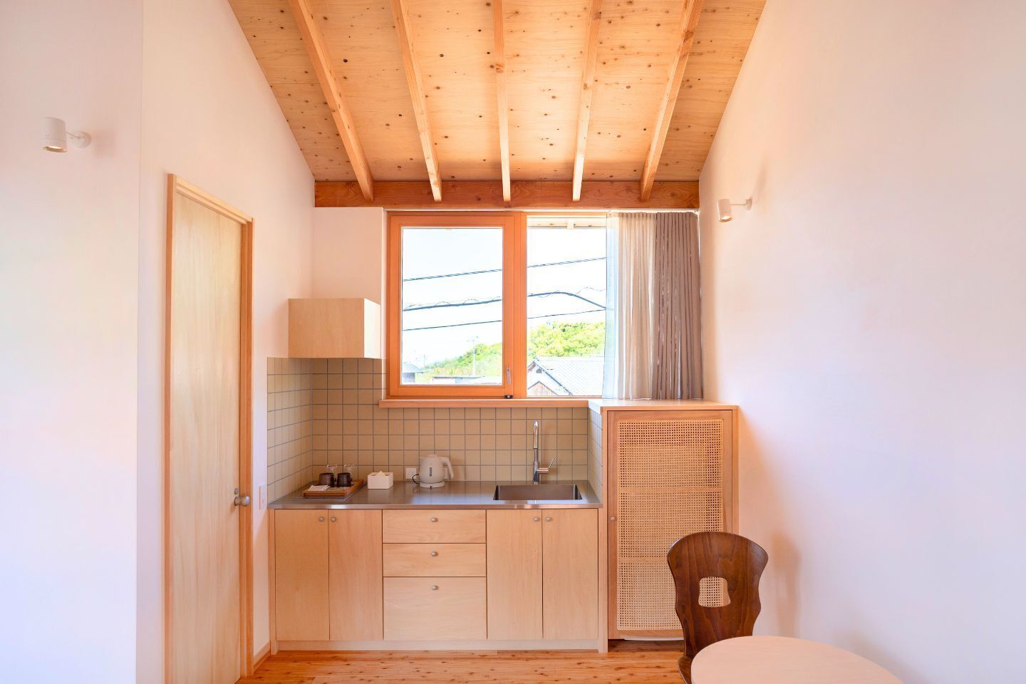 A compact kitchen with wooden cabinets, a window, and a built-in heater.