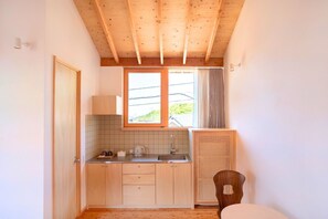 Una cocina compacta con armarios de madera, un ventanal y un calentador integrado.