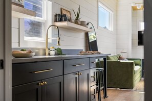 A modern kitchen with dark cabinetry, a gold faucet, and a countertop with various items.