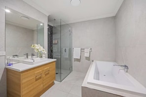 Un baño moderno con tocador doble, cabina de ducha de cristal y bañera independiente.