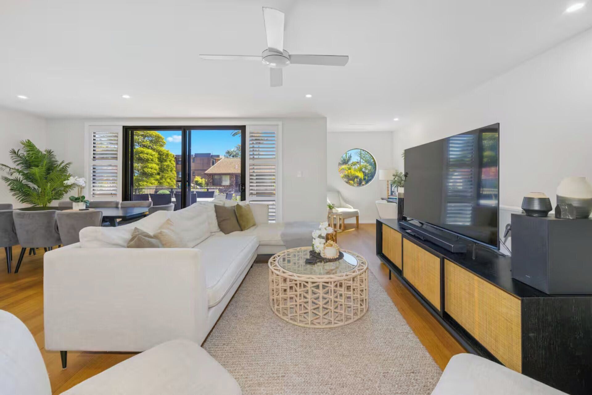 Un salon moderne comprenant un canapé, une table basse, un téléviseur et un balcon aménagé avec du mobilier d’extérieur.