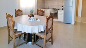 Ruokailutila, jossa on pyöreä pöytä, tuoleja ja hedelmäkulho.