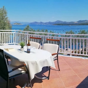 Eine Terrasse mit Tisch für zwei Personen, mit Blick auf ein Gewässer und entferntes Land.
