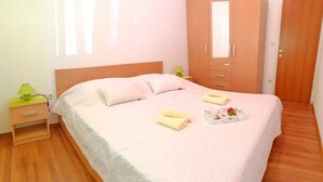 Hotellihuone, jossa on sänky, vaatekaappi, yöpöytä ja lamppu.
