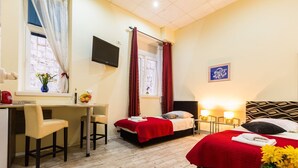 A hotel room with a desk, two beds, a TV, and a window with curtains. - Charming and Historic Old Town Apartments - Twin Room (Zadar)