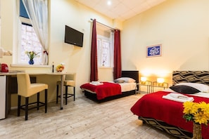 A hotel room with a desk, two beds, a TV, and a window with curtains. - Charming and Historic Old Town Apartments - Twin Room (Zadar)