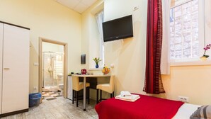 A hotel room with a bed, a desk, a chair, a TV, and a window with curtains. - Charming and Historic Old Town Apartments - Twin Room (Zadar)