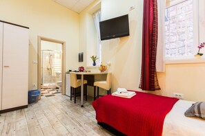 A hotel room with a bed, a desk, a chair, a TV, and a window with curtains. - Charming and Historic Old Town Apartments - Twin Room (Zadar)
