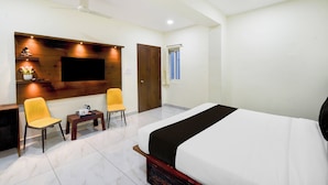 Habitación de hotel con cama, dos sillas, una mesita, televisión y ventana.