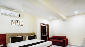 Habitación de hotel con una cama, un sofá rojo, un cabecero de madera y un aire acondicionado instalado en la pared.