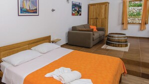 A bedroom with a bed, a sofa, a wooden cabinet, and a barrel. - Holiday Home Stari Zoganj - Two Bedroom Holiday Home With Terrace and Swimming Pool (Orebic)